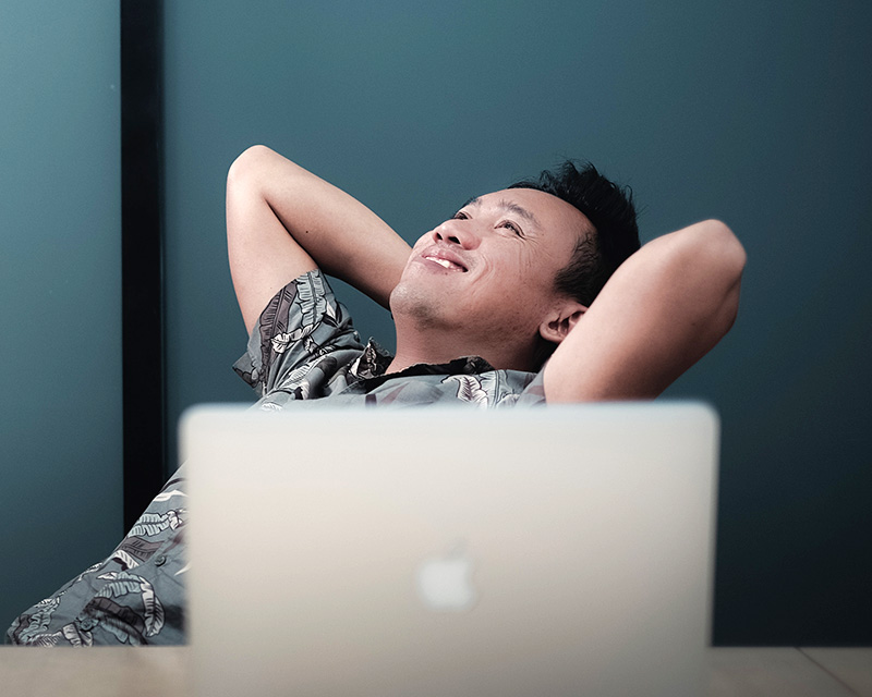 Man leaning back in desk chair and smiling